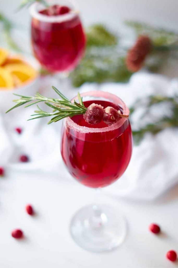 deep red holiday cocktail with cranberries on a white background