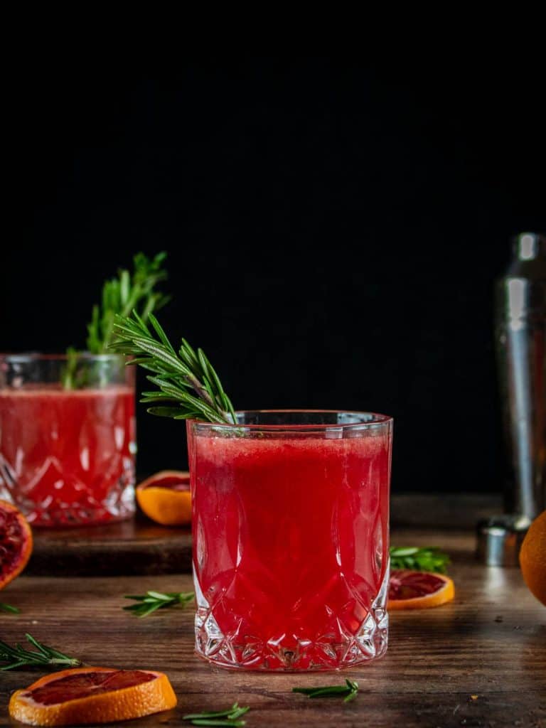 blood orange whiskey cocktail in a short glass on a black background